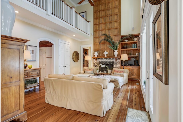 living room featuring a fireplace, crown molding, hardwood / wood-style floors, and a towering ceiling