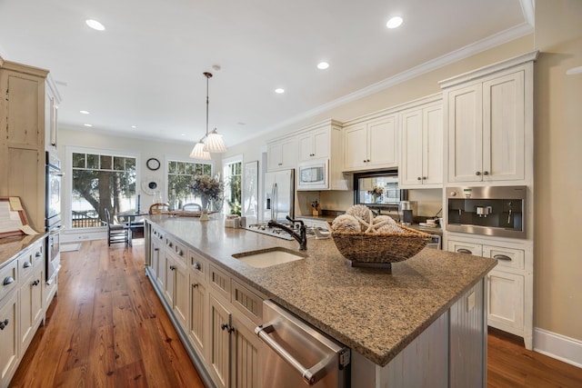 kitchen with light stone countertops, appliances with stainless steel finishes, a spacious island, sink, and decorative light fixtures