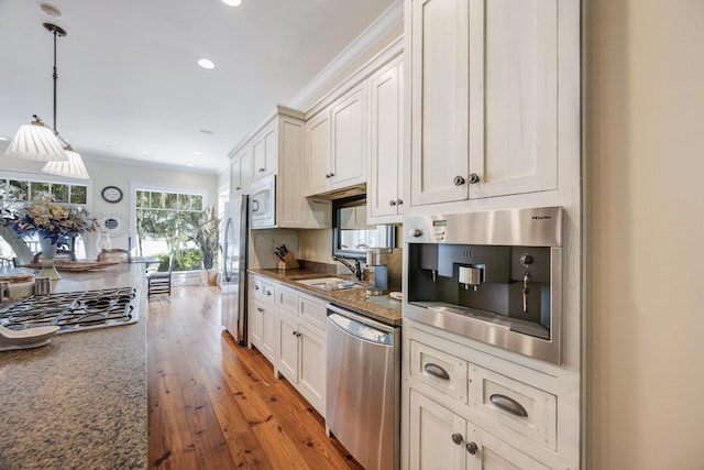 kitchen with white cabinetry, pendant lighting, stainless steel appliances, and light wood-type flooring