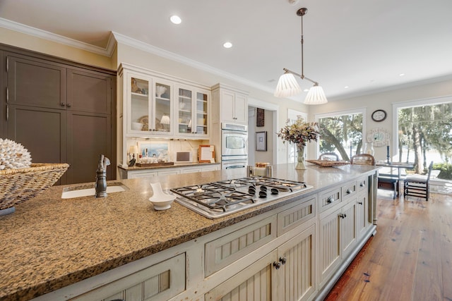 kitchen with pendant lighting, double oven, ornamental molding, and stainless steel gas cooktop