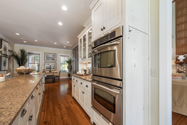 kitchen featuring light stone countertops, white cabinetry, ornamental molding, and stainless steel double oven