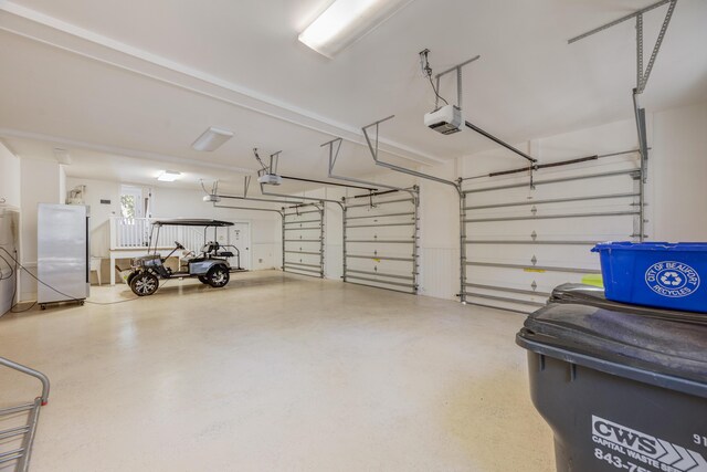 garage featuring stainless steel fridge and a garage door opener