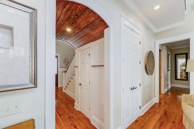 corridor featuring light wood-type flooring, ornamental molding, and wood ceiling