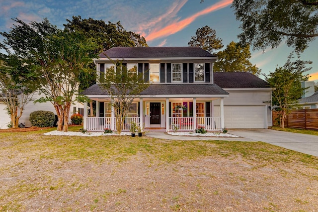 colonial home featuring fence, a lawn, covered porch, and concrete driveway