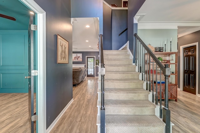 staircase with baseboards, ornamental molding, and wood finished floors