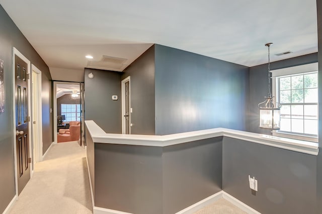corridor with baseboards, light carpet, and visible vents