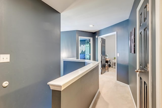 hallway featuring baseboards and light carpet