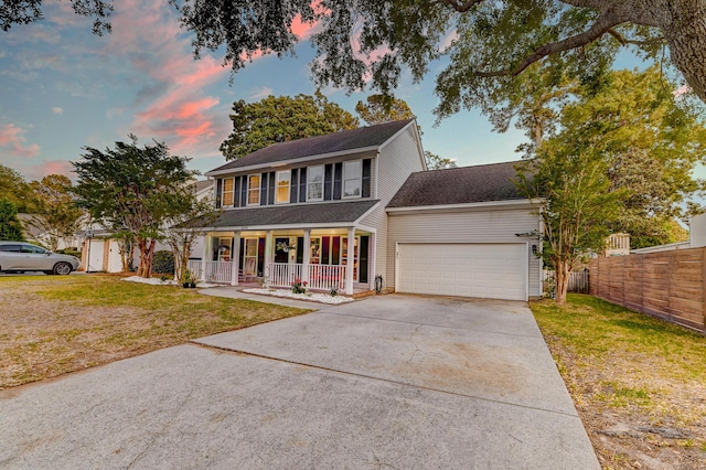 colonial house featuring a garage, fence, a front yard, concrete driveway, and a porch