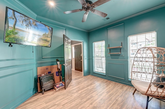 foyer featuring ceiling fan, light wood-style floors, a decorative wall, visible vents, and ornamental molding