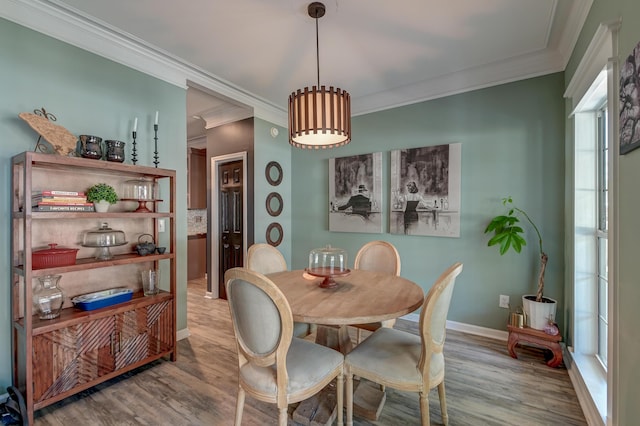 dining space featuring crown molding, baseboards, and wood finished floors