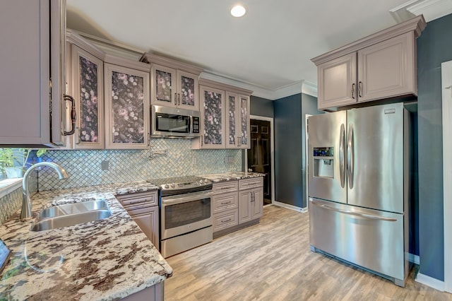 kitchen featuring glass insert cabinets, baseboards, tasteful backsplash, a sink, and stainless steel appliances