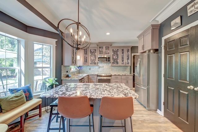 kitchen featuring light stone countertops, appliances with stainless steel finishes, a kitchen breakfast bar, tasteful backsplash, and glass insert cabinets
