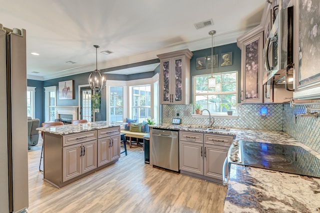 kitchen featuring visible vents, appliances with stainless steel finishes, light wood-type flooring, a sink, and ornamental molding