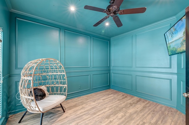 living area featuring ornamental molding, wood finished floors, and a decorative wall