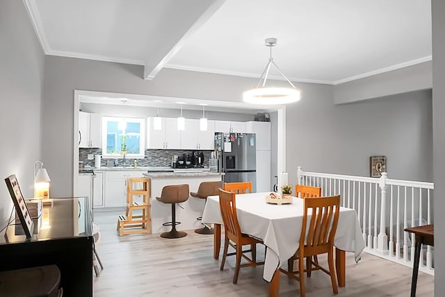 dining room featuring beam ceiling, light wood-type flooring, and sink