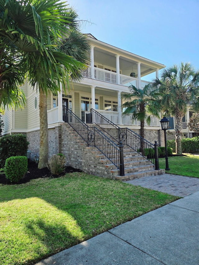 view of front of house featuring stairway, a balcony, a porch, and a front lawn