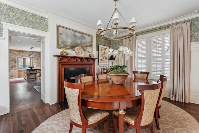 dining room with an inviting chandelier, ornamental molding, dark hardwood / wood-style floors, and brick wall