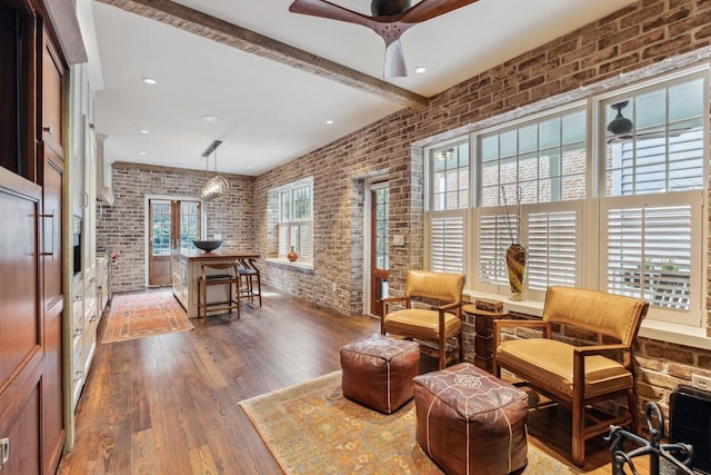 living area featuring brick wall, dark wood-type flooring, ceiling fan, and plenty of natural light