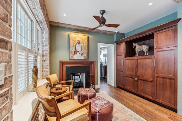 living area featuring plenty of natural light, light hardwood / wood-style floors, ceiling fan, and a multi sided fireplace