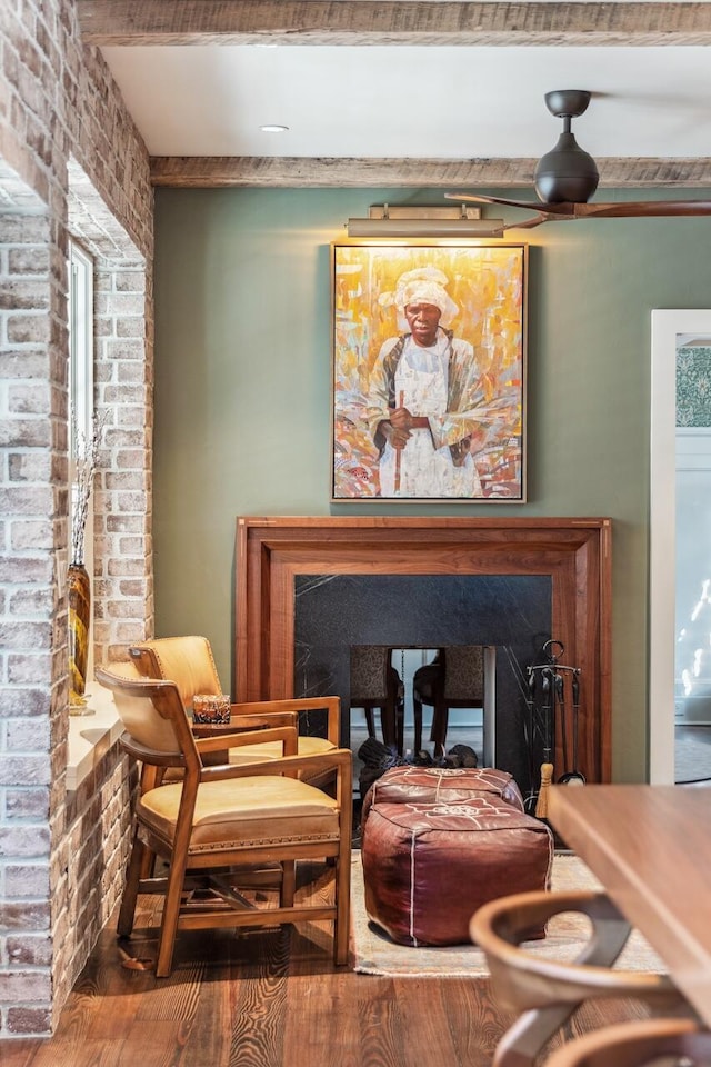 living area featuring brick wall, wood-type flooring, and beam ceiling