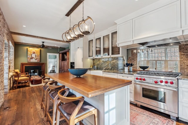 kitchen with hanging light fixtures, a kitchen breakfast bar, designer range, white cabinets, and a kitchen island