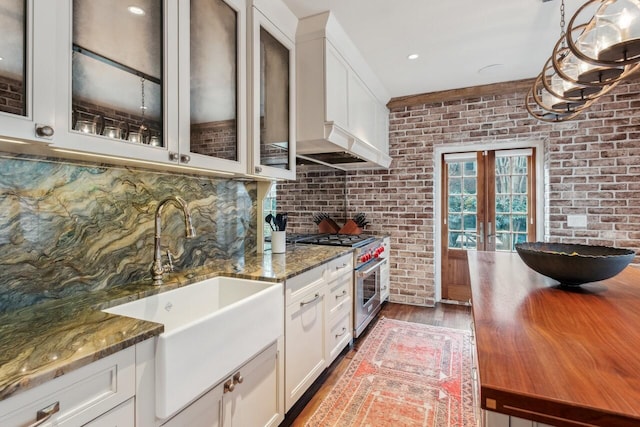 kitchen with white cabinetry, high end stove, and dark stone countertops