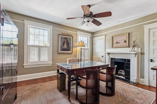 dining room featuring a tiled fireplace, dark wood-type flooring, and ceiling fan