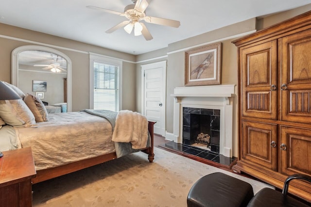 bedroom featuring ceiling fan and a tiled fireplace