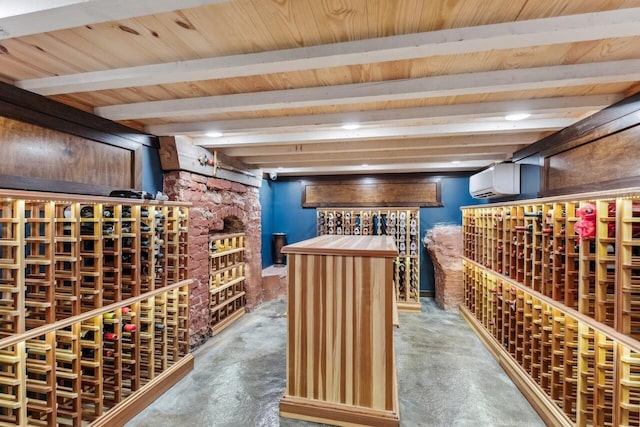 wine room featuring beamed ceiling, an AC wall unit, and concrete floors