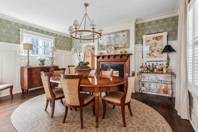 dining space featuring an inviting chandelier, crown molding, dark wood-type flooring, and a premium fireplace