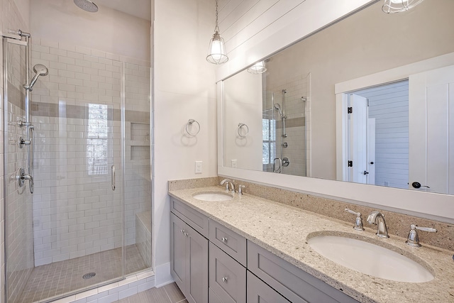 full bathroom featuring double vanity, a stall shower, and a sink