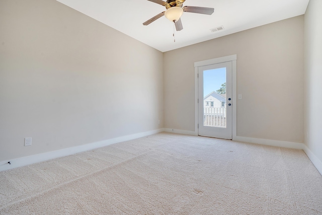 spare room with light carpet, ceiling fan, visible vents, and baseboards