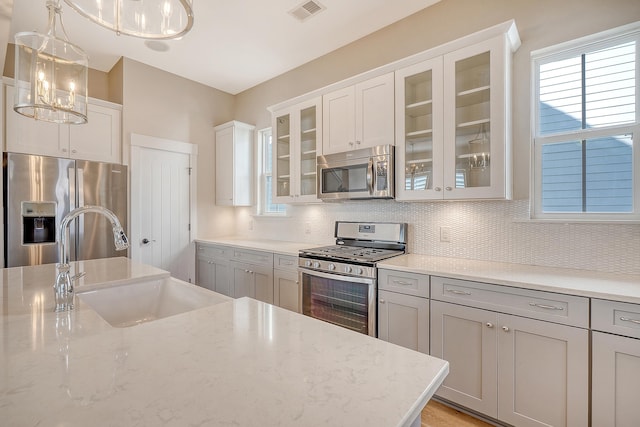 kitchen with decorative light fixtures, visible vents, decorative backsplash, appliances with stainless steel finishes, and a sink