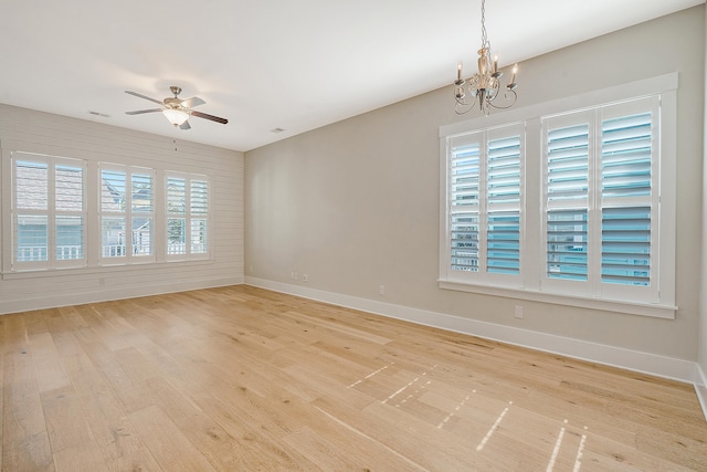 unfurnished room featuring visible vents, light wood-style flooring, baseboards, and ceiling fan with notable chandelier