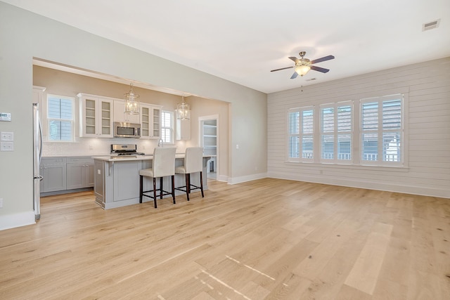 kitchen with visible vents, appliances with stainless steel finishes, a kitchen breakfast bar, light countertops, and light wood-type flooring