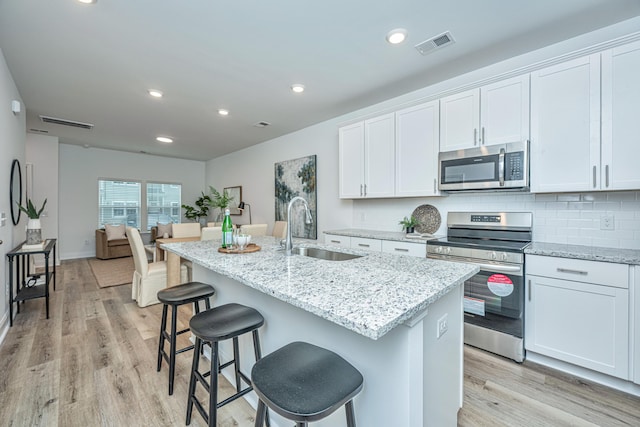 kitchen with sink, stainless steel appliances, an island with sink, and white cabinets