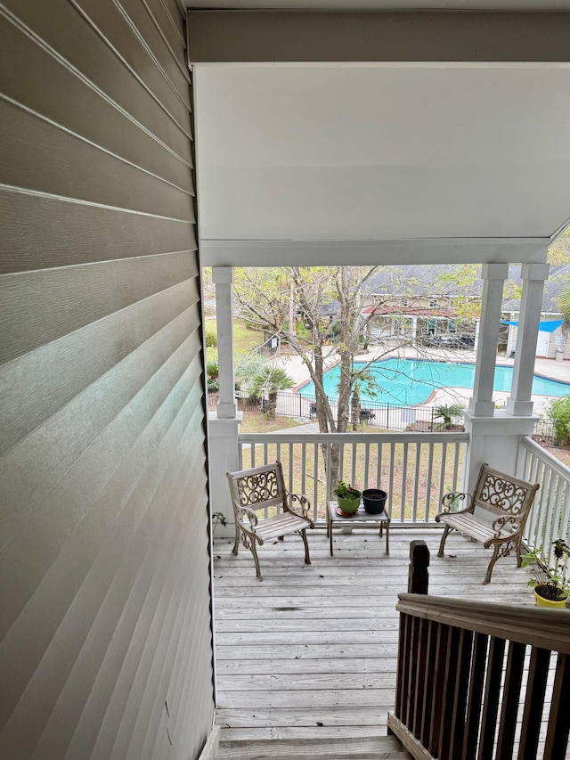 deck featuring fence and a community pool