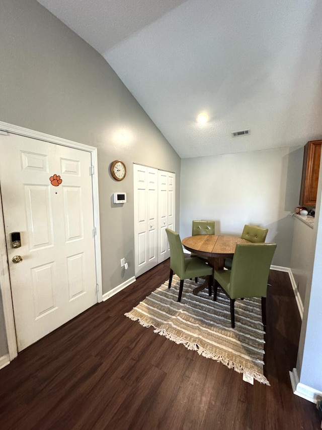 dining area featuring baseboards, visible vents, vaulted ceiling, and dark wood finished floors