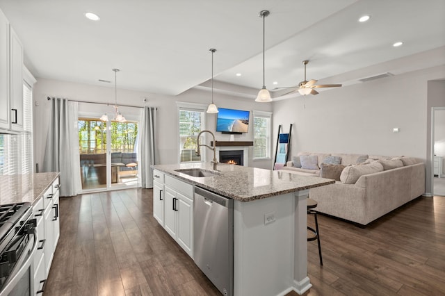 kitchen with a kitchen island with sink, sink, white cabinets, and appliances with stainless steel finishes