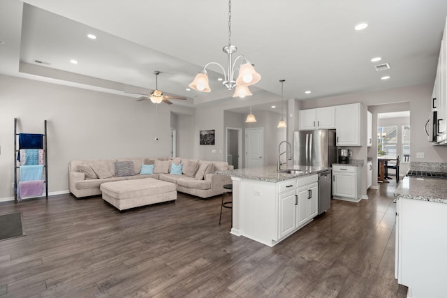 kitchen with stainless steel appliances, white cabinetry, hanging light fixtures, and a kitchen island with sink