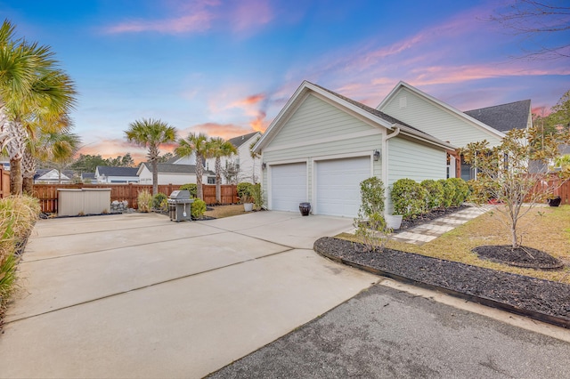 view of home's exterior featuring a garage, concrete driveway, and fence