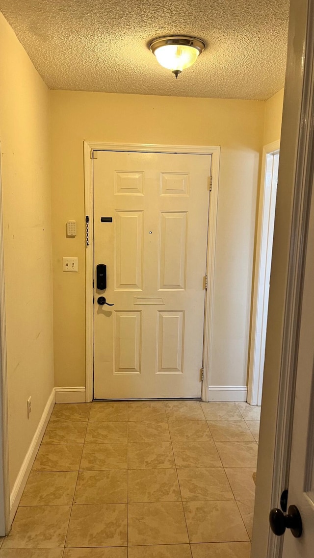 doorway with light tile patterned floors, baseboards, and a textured ceiling