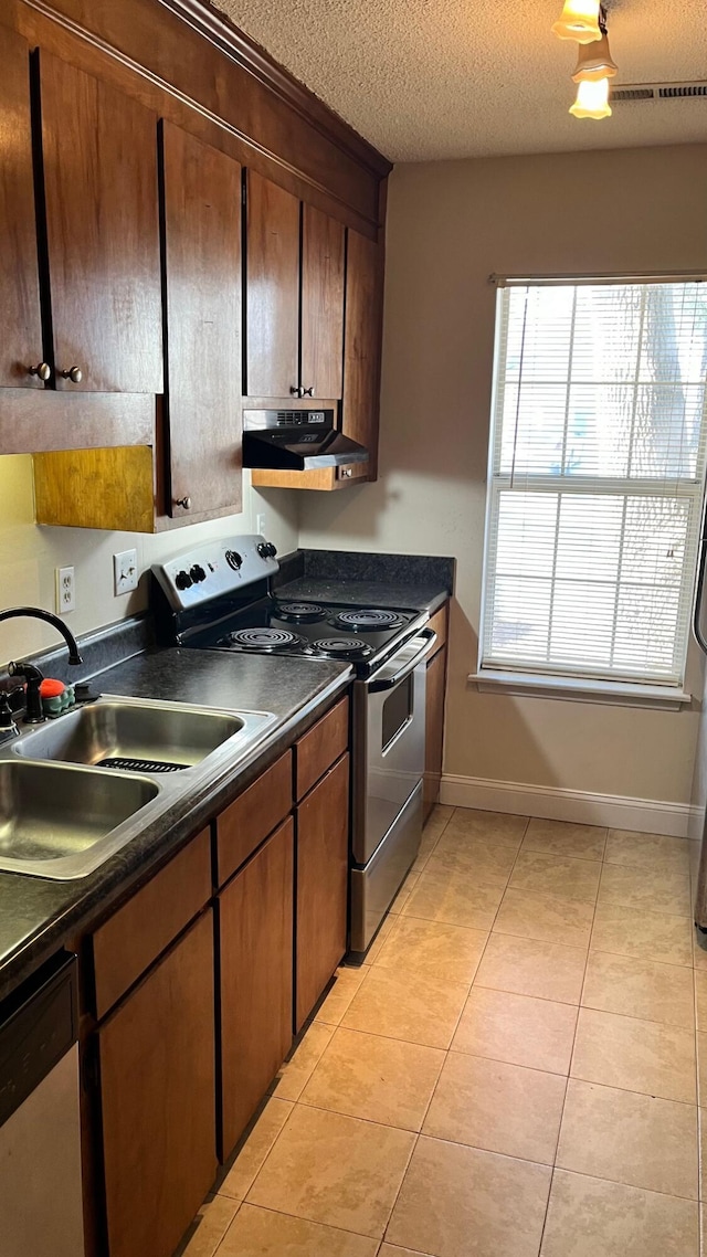 kitchen with light tile patterned floors, dark countertops, electric range oven, a sink, and under cabinet range hood