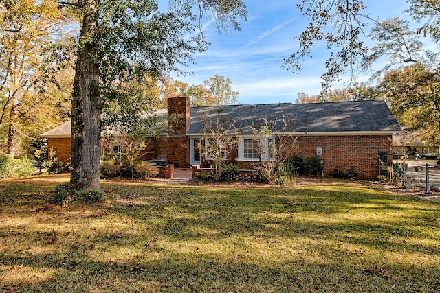 rear view of house featuring brick siding and a lawn