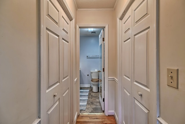 hall with light wood-type flooring, baseboards, and ornamental molding