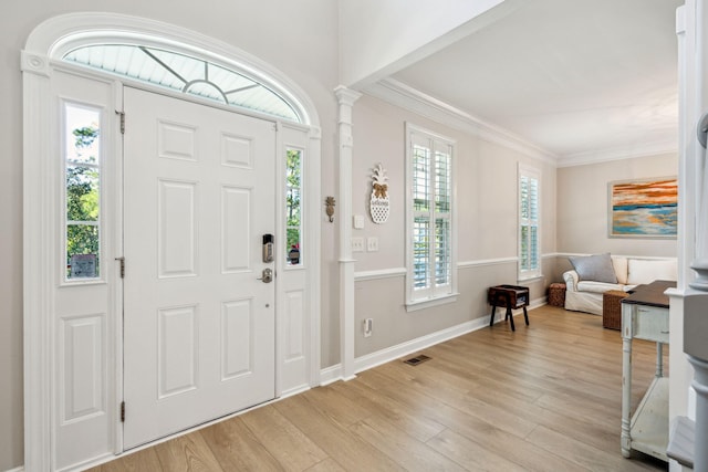 entrance foyer featuring crown molding, decorative columns, and light hardwood / wood-style flooring