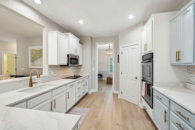 kitchen featuring sink, white cabinetry, light wood-type flooring, appliances with stainless steel finishes, and light stone countertops