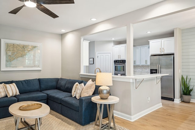 living room with ceiling fan and light hardwood / wood-style flooring