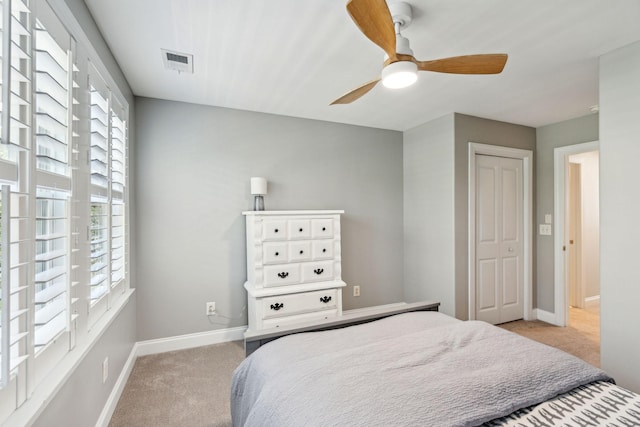 bedroom featuring light colored carpet, a closet, and ceiling fan