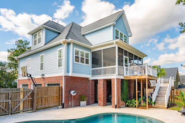 rear view of house with a fenced in pool, a sunroom, and a patio area